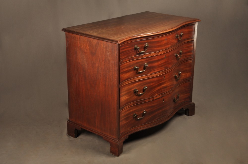 An 18th-century Georgian mahogany serpentine chest of drawers featuring four graduated drawers, brass swan-neck handles, and bracket feet. View II