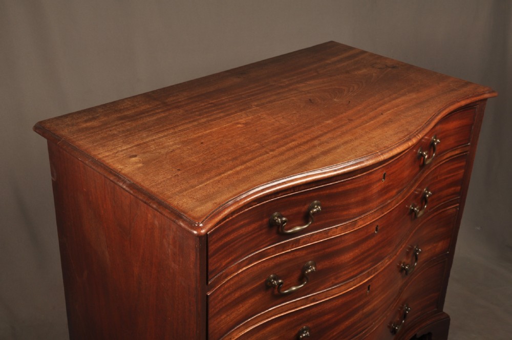 An 18th-century Georgian mahogany serpentine chest of drawers featuring four graduated drawers, brass swan-neck handles, and bracket feet. View III