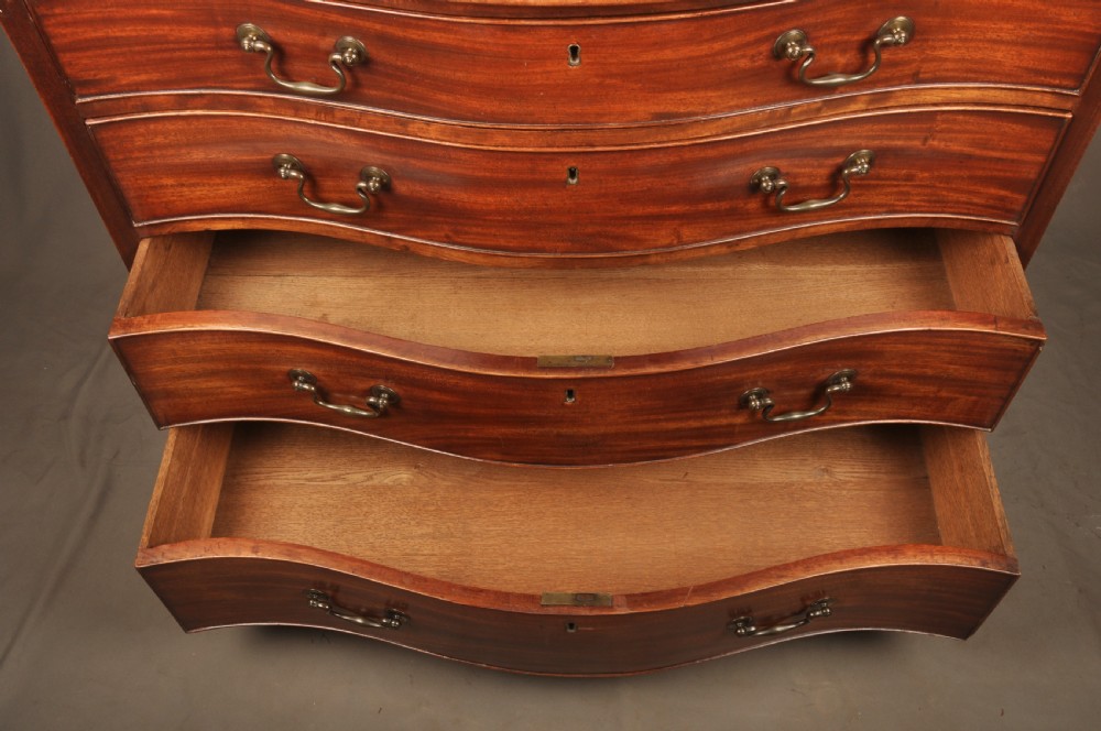 An 18th-century Georgian mahogany serpentine chest of drawers featuring four graduated drawers, brass swan-neck handles, and bracket feet. View VII