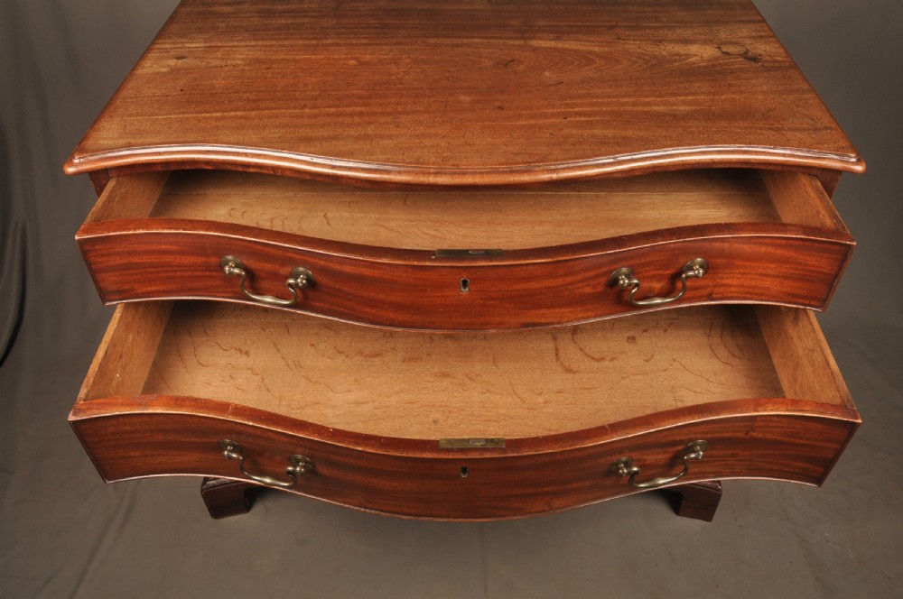 An 18th-century Georgian mahogany serpentine chest of drawers featuring four graduated drawers, brass swan-neck handles, and bracket feet. View VIII