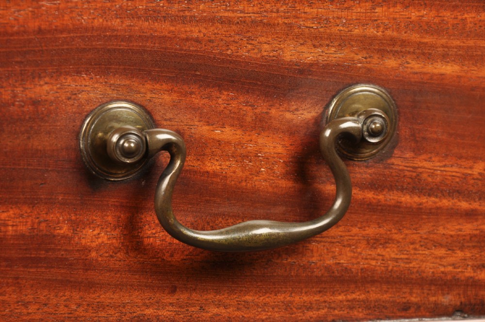 An 18th-century Georgian mahogany serpentine chest of drawers featuring four graduated drawers, brass swan-neck handles, and bracket feet. View X