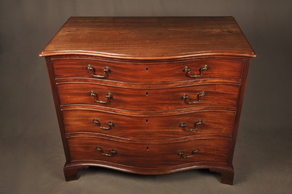 An 18th-century Georgian mahogany serpentine chest of drawers featuring four graduated drawers, brass swan-neck handles, and bracket feet. View XI