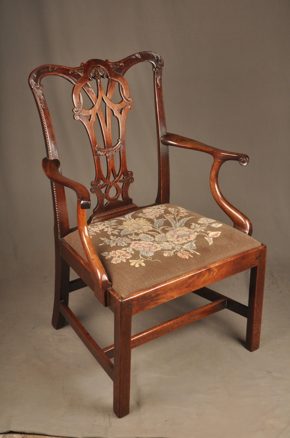 An 18th-century Georgian Chippendale mahogany armchair featuring a carved pierced splat back, shaped arms, and a floral needlepoint drop-in seat. View II