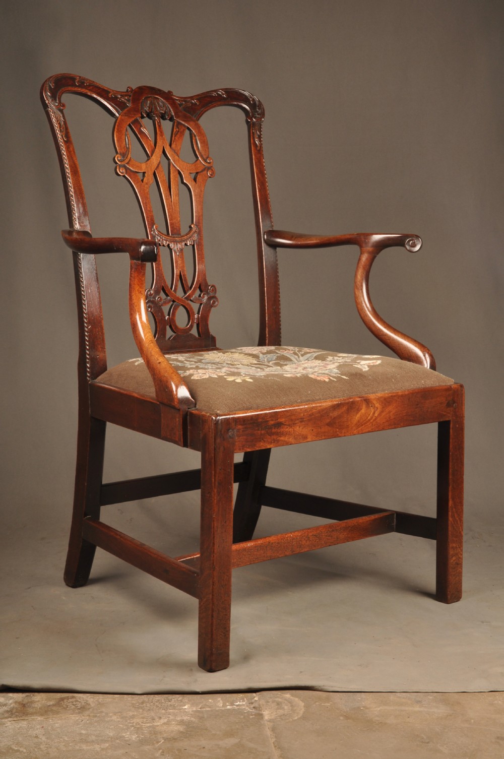 An 18th-century Georgian Chippendale mahogany armchair featuring a carved pierced splat back, shaped arms, and a floral needlepoint drop-in seat. View IV