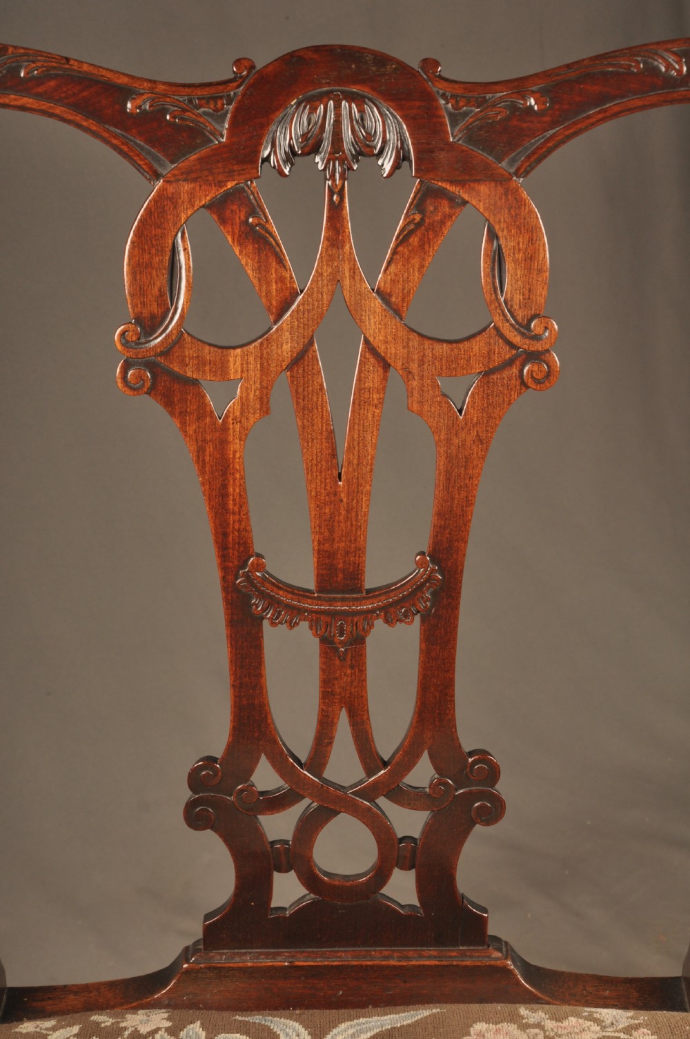 An 18th-century Georgian Chippendale mahogany armchair featuring a carved pierced splat back, shaped arms, and a floral needlepoint drop-in seat. View VII