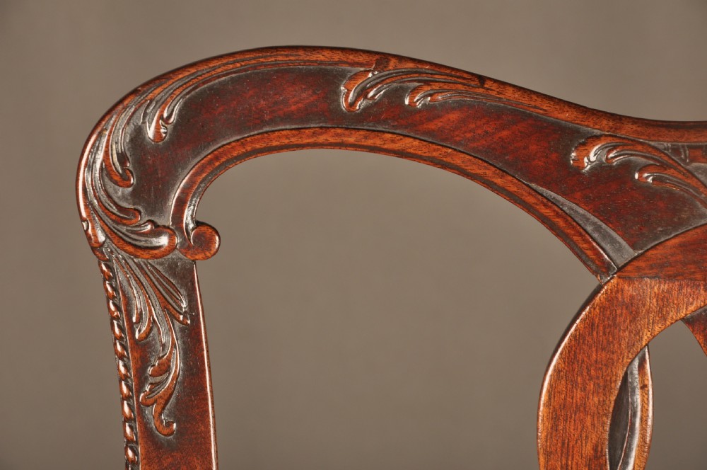 An 18th-century Georgian Chippendale mahogany armchair featuring a carved pierced splat back, shaped arms, and a floral needlepoint drop-in seat. View X
