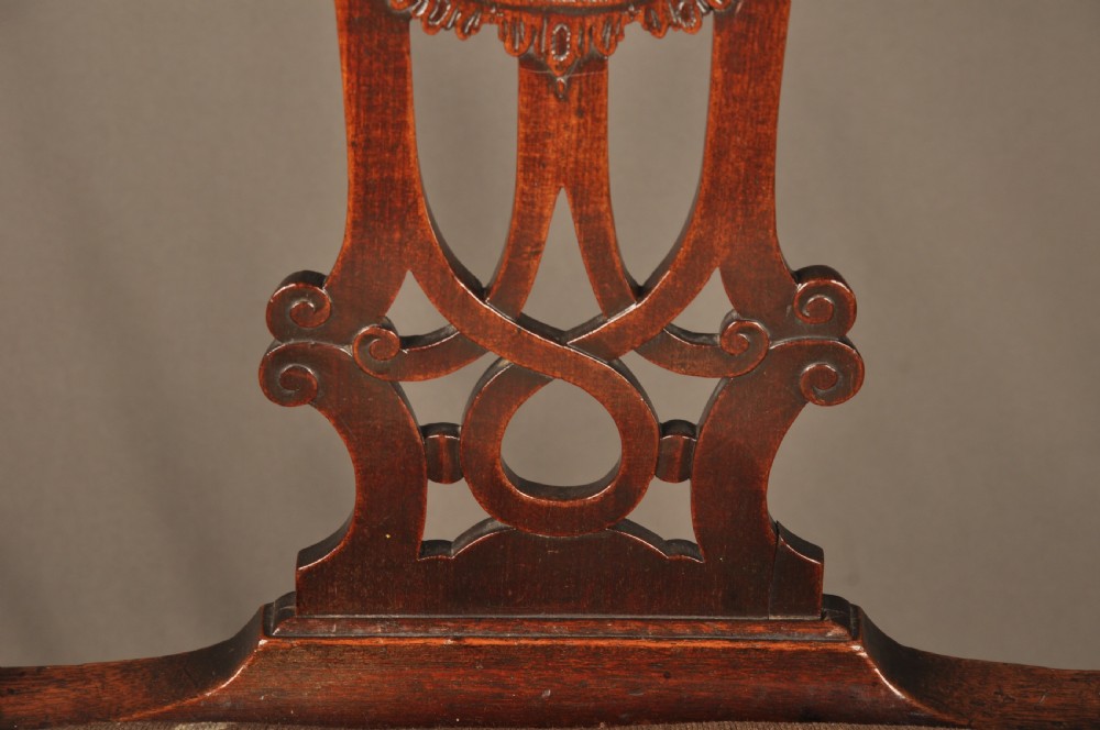 An 18th-century Georgian Chippendale mahogany armchair featuring a carved pierced splat back, shaped arms, and a floral needlepoint drop-in seat. View XII