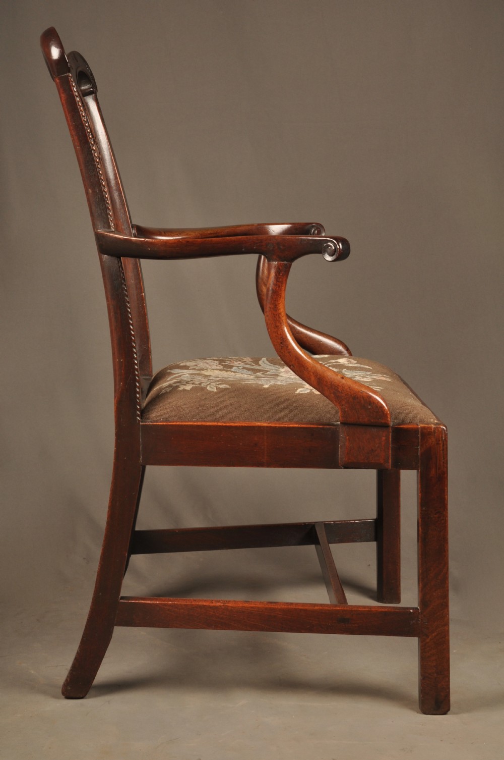An 18th-century Georgian Chippendale mahogany armchair featuring a carved pierced splat back, shaped arms, and a floral needlepoint drop-in seat. View XIV