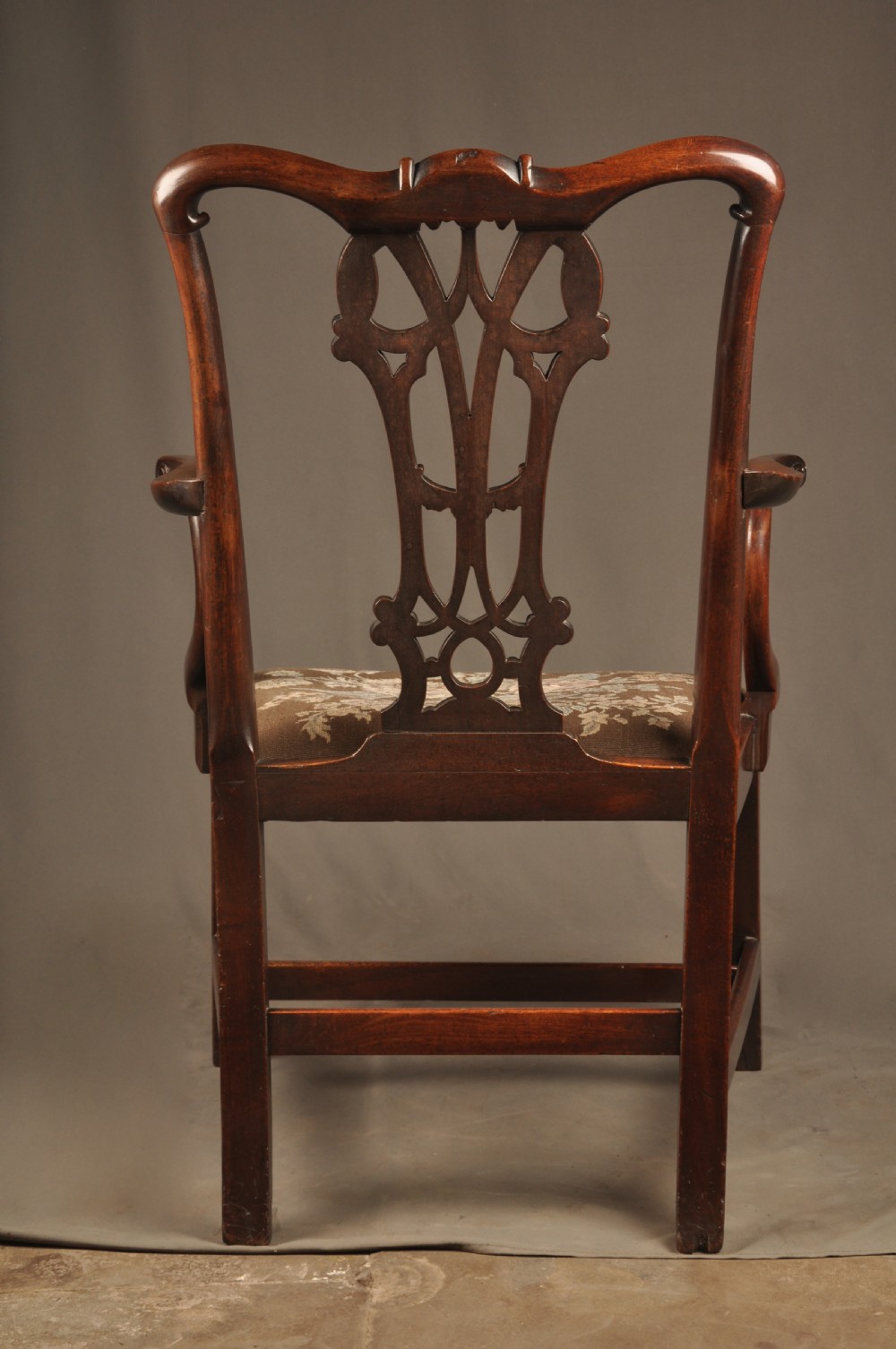 An 18th-century Georgian Chippendale mahogany armchair featuring a carved pierced splat back, shaped arms, and a floral needlepoint drop-in seat. View XV