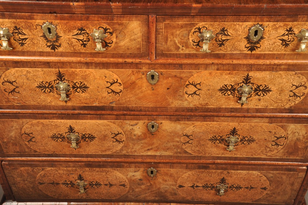 A late 17th-century walnut chest of drawers featuring arabesque marquetry inlays, tear-drop brass handles, and ebonised bun feet. View IV