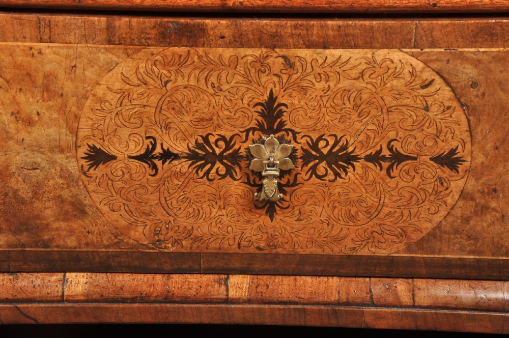 A late 17th-century walnut chest of drawers featuring arabesque marquetry inlays, tear-drop brass handles, and ebonised bun feet. View V