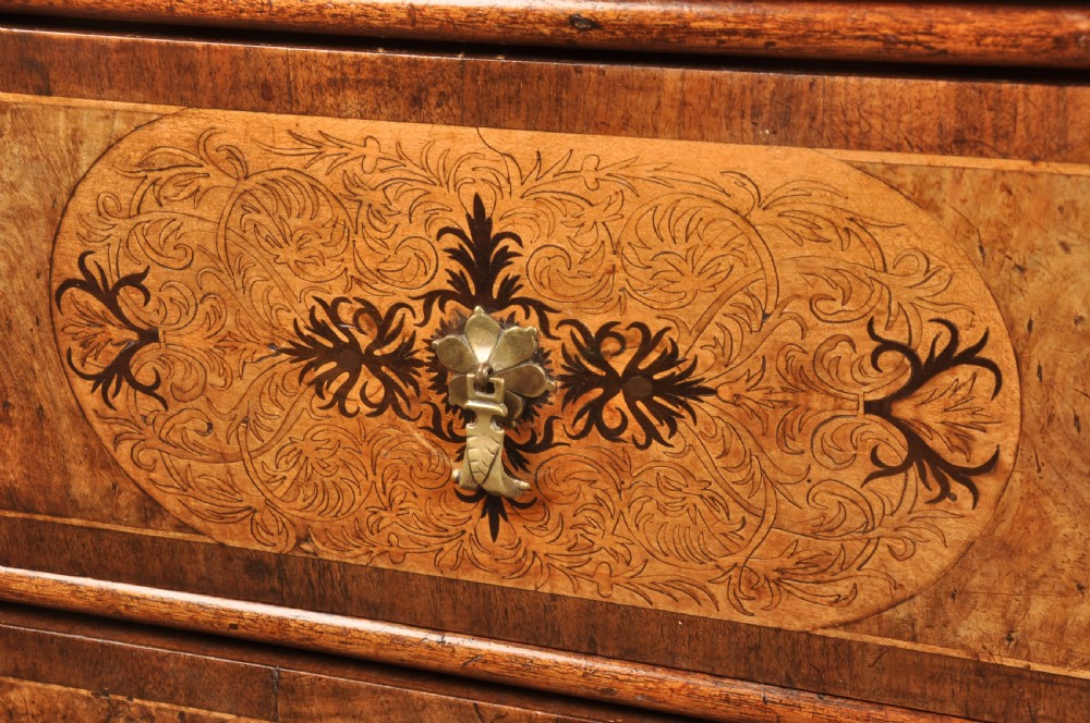 A late 17th-century walnut chest of drawers featuring arabesque marquetry inlays, tear-drop brass handles, and ebonised bun feet. View VI