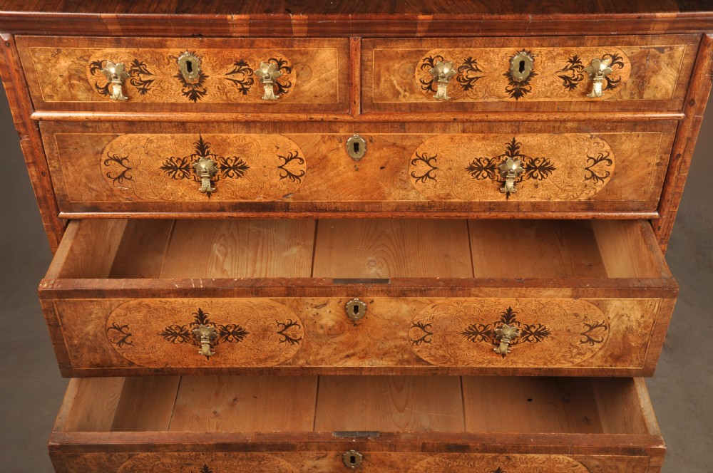 A late 17th-century walnut chest of drawers featuring arabesque marquetry inlays, tear-drop brass handles, and ebonised bun feet. View VII