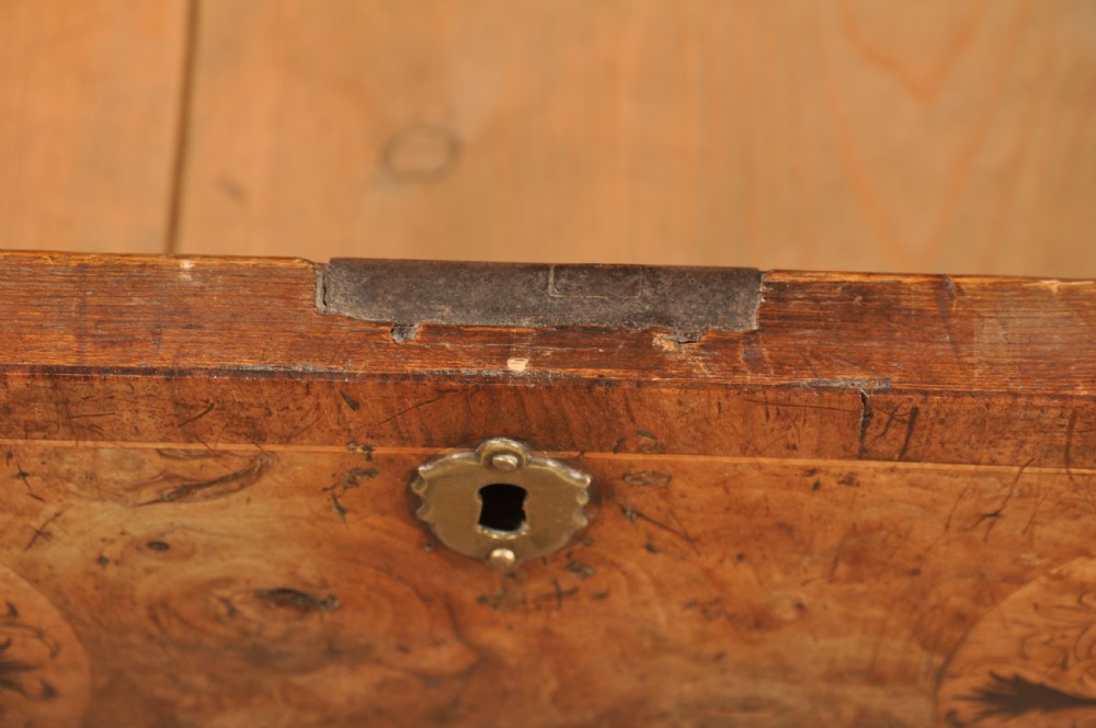 A late 17th-century walnut chest of drawers featuring arabesque marquetry inlays, tear-drop brass handles, and ebonised bun feet. View X