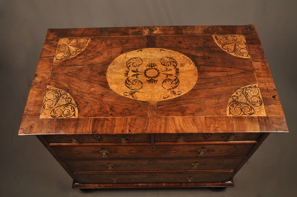 A late 17th-century walnut chest of drawers featuring arabesque marquetry inlays, tear-drop brass handles, and ebonised bun feet. View XI