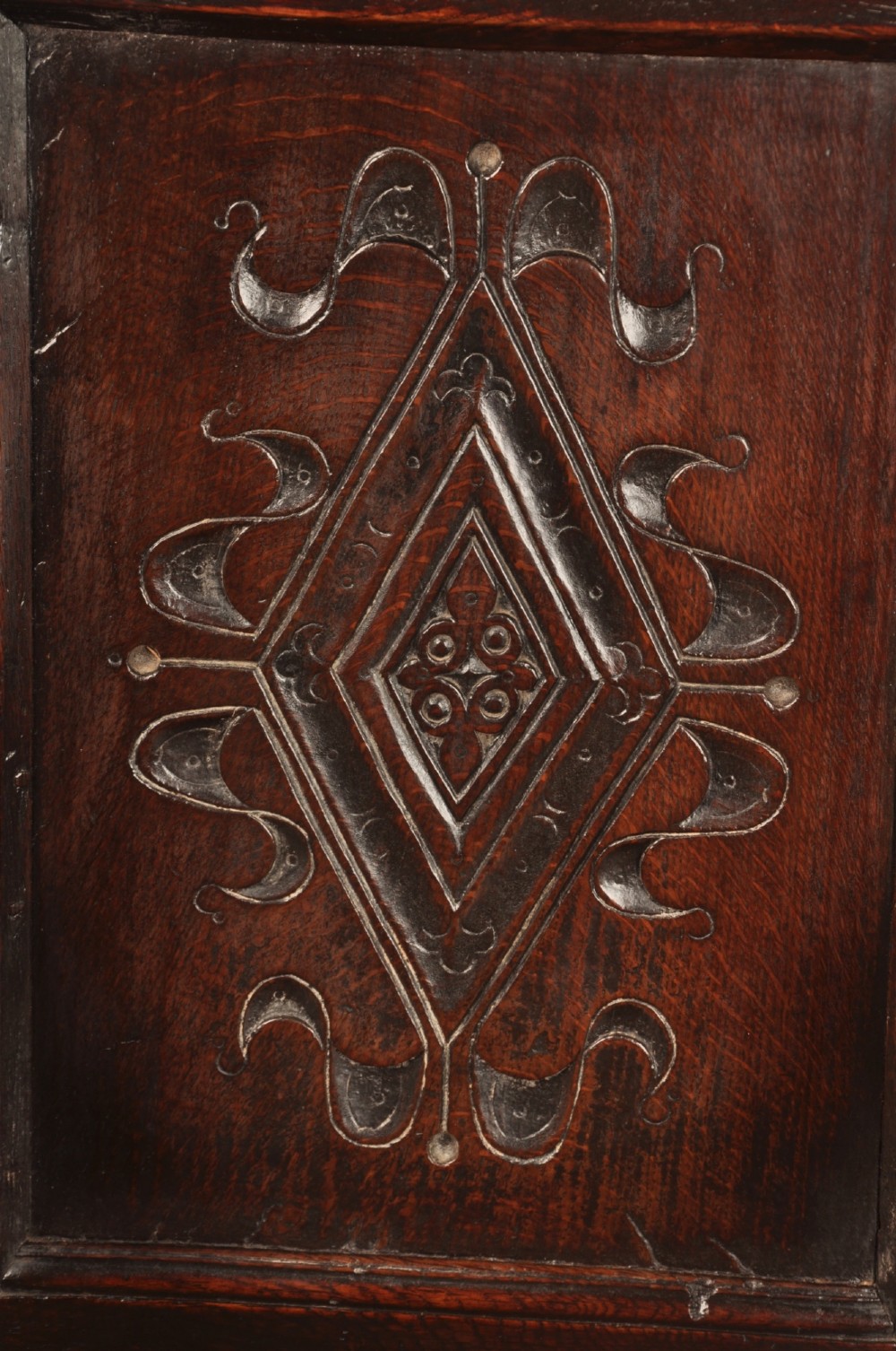 A seventeenth-century carved dark oak wainscot armchair featuring a carved lozenge motif on the back panel, scrolled cresting rail, shaped armrests, and turned front legs. View IV