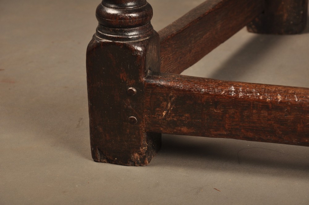 A seventeenth-century carved dark oak wainscot armchair featuring a carved lozenge motif on the back panel, scrolled cresting rail, shaped armrests, and turned front legs. View VI