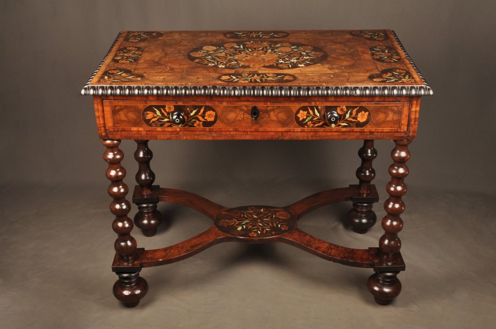 An antique brown walnut centre table featuring detailed floral marquetry inlays across the tabletop, single drawer front, and stretcher base, supported by bobbin-turned legs.