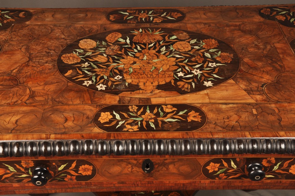 An antique brown walnut centre table featuring detailed floral marquetry inlays across the tabletop, single drawer front, and stretcher base, supported by bobbin-turned legs. View III