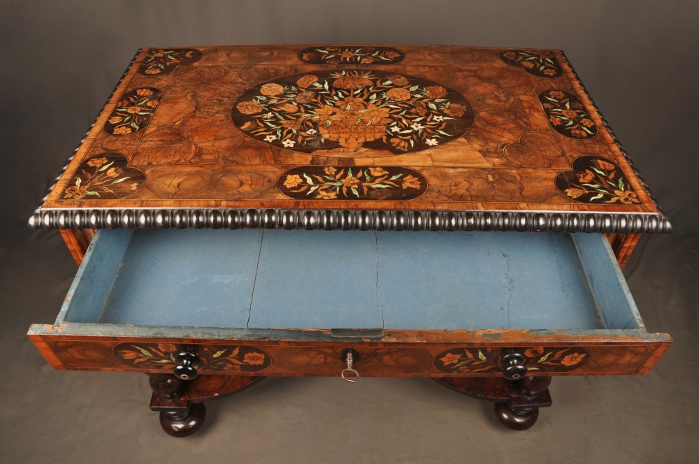 An antique brown walnut centre table featuring detailed floral marquetry inlays across the tabletop, single drawer front, and stretcher base, supported by bobbin-turned legs. View IV