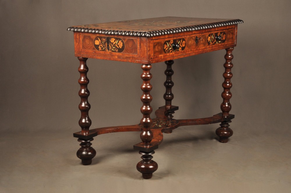 An antique brown walnut centre table featuring detailed floral marquetry inlays across the tabletop, single drawer front, and stretcher base, supported by bobbin-turned legs. View XII