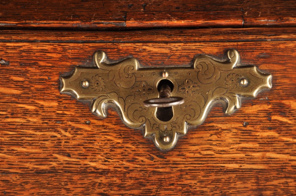 An early 18th-century oak bureau featuring a slant-front writing flap above two short and two long drawers with brass hardware. View VII