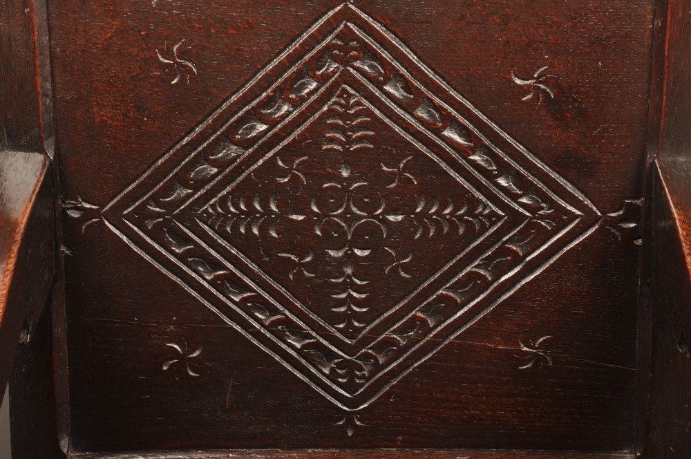 A 17th-century dark oak wainscot armchair featuring a carved lozenge back panel, turned front supports, and shaped armrests. View IV