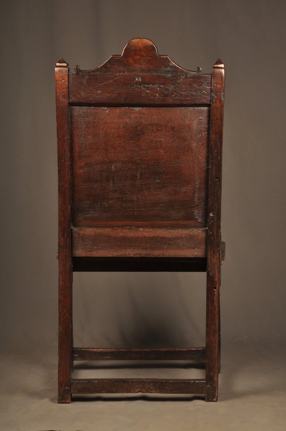 A 17th-century dark oak wainscot armchair featuring a carved lozenge back panel, turned front supports, and shaped armrests. View X