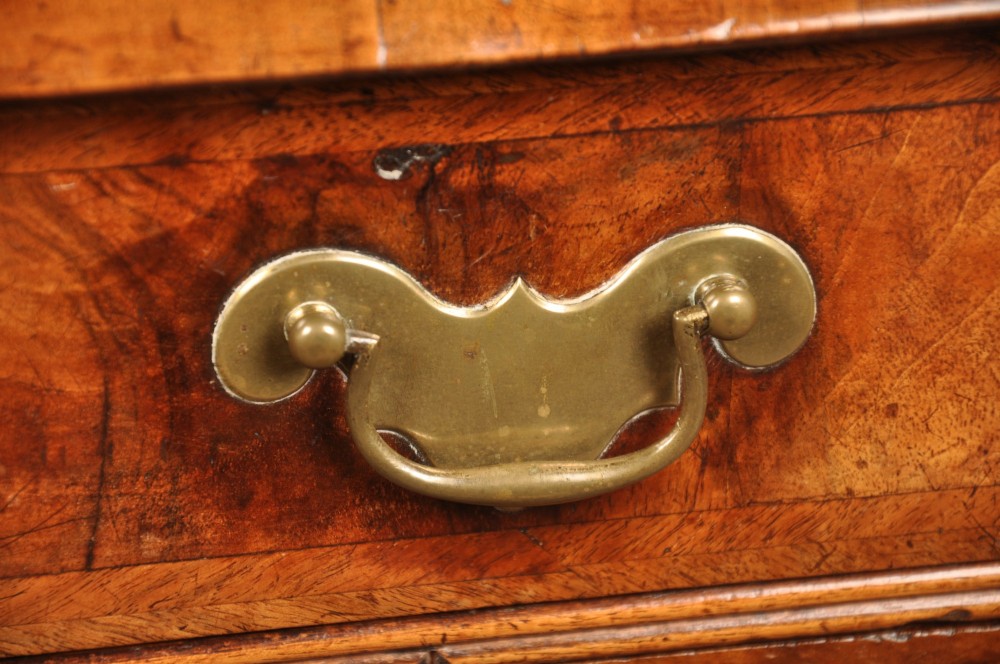 A Queen Anne walnut kneehole desk featuring figured wood veneers, seven drawers with brass handles, a central recessed cupboard, and bracket feet. View XI