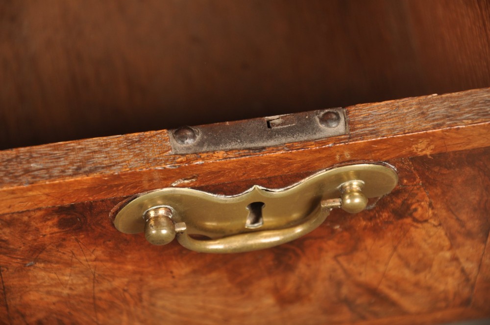 A Queen Anne walnut kneehole desk featuring figured wood veneers, seven drawers with brass handles, a central recessed cupboard, and bracket feet. View XII