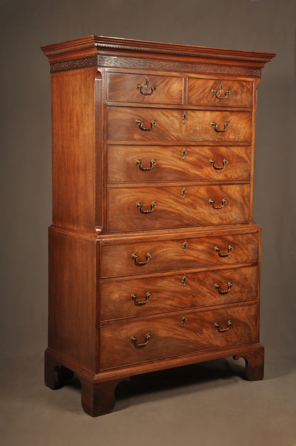 An 18th-century Georgian mahogany tallboy chest-on-chest with flame mahogany drawer fronts, brass swan-neck handles, fluted quarter columns, and bracket feet.