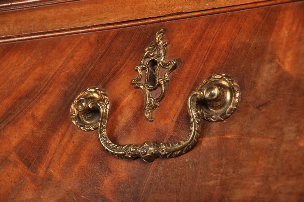 An 18th-century Georgian mahogany tallboy chest-on-chest with flame mahogany drawer fronts, brass swan-neck handles, fluted quarter columns, and bracket feet. View V