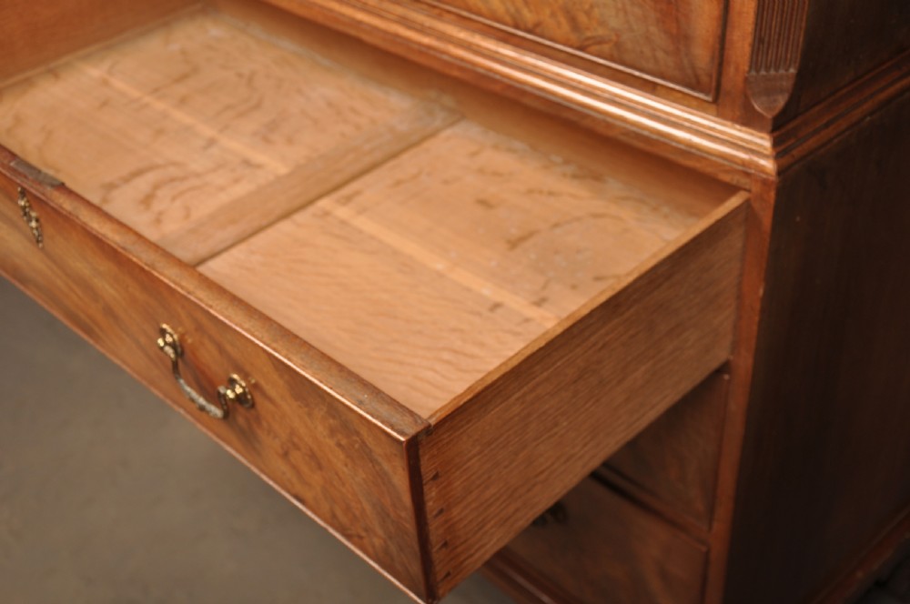 An 18th-century Georgian mahogany tallboy chest-on-chest with flame mahogany drawer fronts, brass swan-neck handles, fluted quarter columns, and bracket feet. View IX