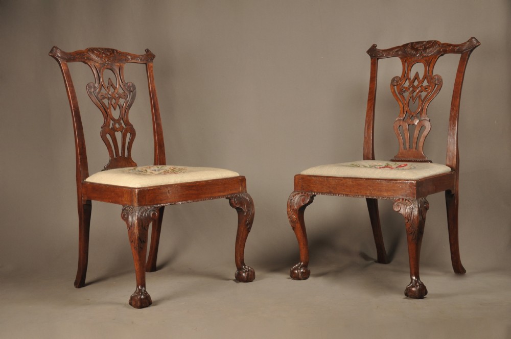 A pair of 18th-century George II mahogany side chairs featuring pierced carved splats, cabriole legs with claw and ball feet, and floral needlepoint drop-in seats. View IV