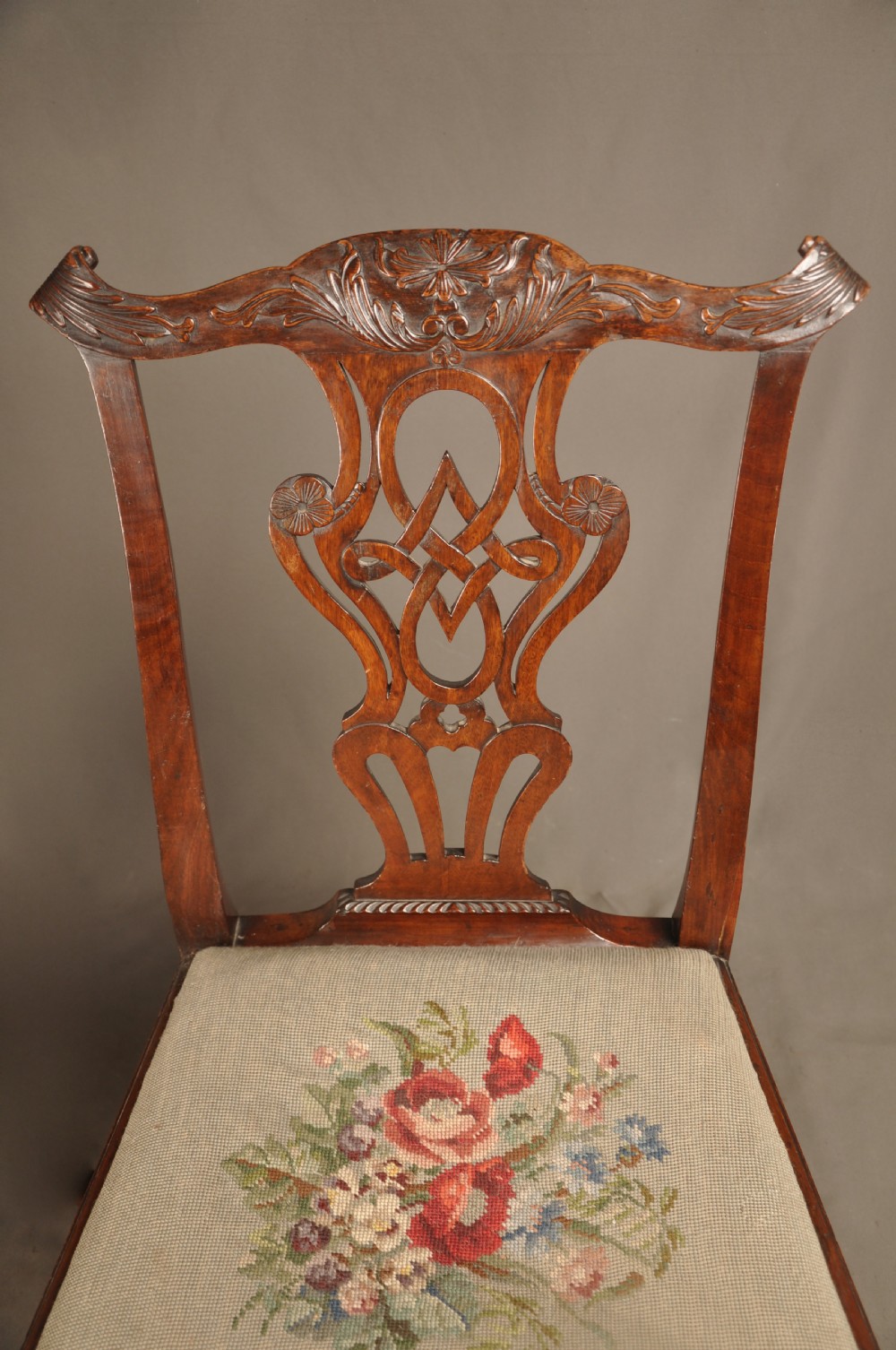 A pair of 18th-century George II mahogany side chairs featuring pierced carved splats, cabriole legs with claw and ball feet, and floral needlepoint drop-in seats. View VI