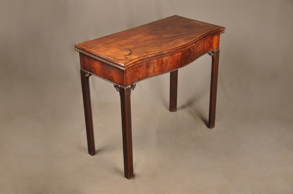 An 18th-century Georgian mahogany card table with a folded serpentine top and fluted legs. View II