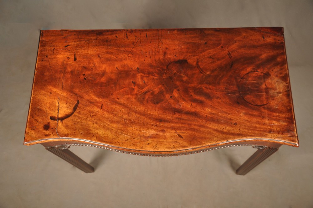 An 18th-century Georgian mahogany card table with a folded serpentine top and fluted legs. View X