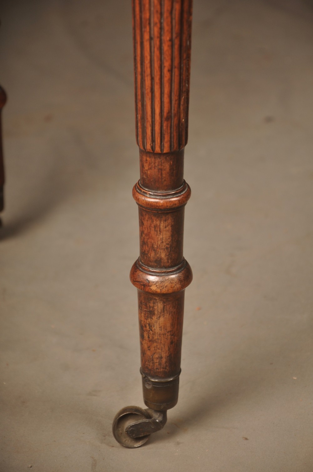 A late eighteenth-century mahogany fold-over card table featuring satinwood inlay, a reeded apron, and fluted legs on brass castors. View V