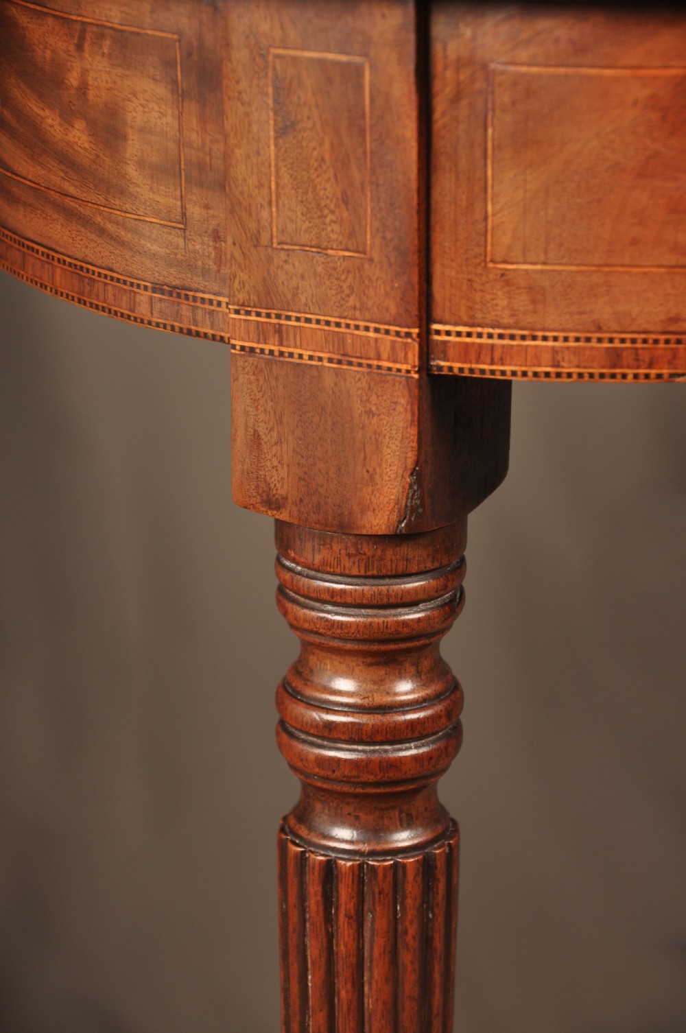 A late eighteenth-century mahogany fold-over card table featuring satinwood inlay, a reeded apron, and fluted legs on brass castors. View VI