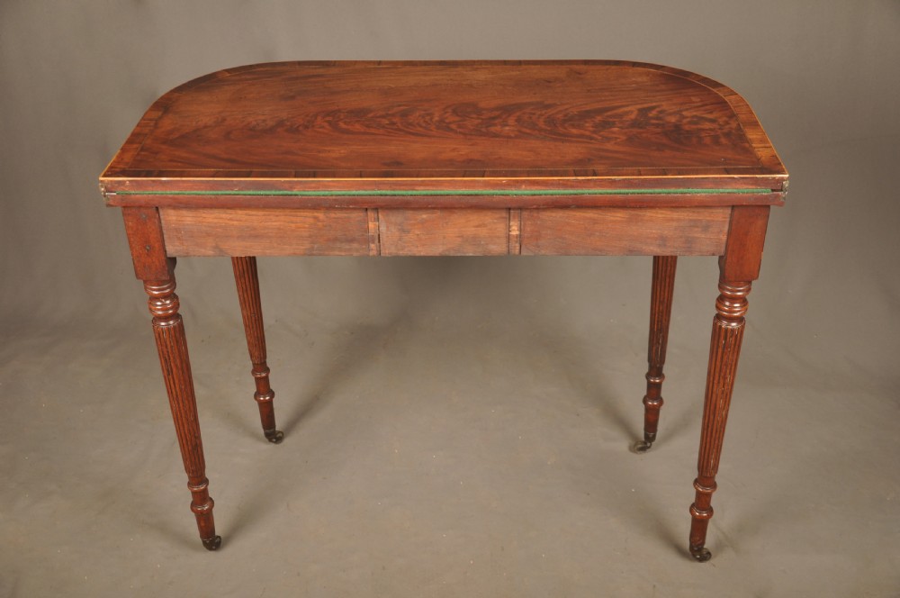 A late eighteenth-century mahogany fold-over card table featuring satinwood inlay, a reeded apron, and fluted legs on brass castors. View XII
