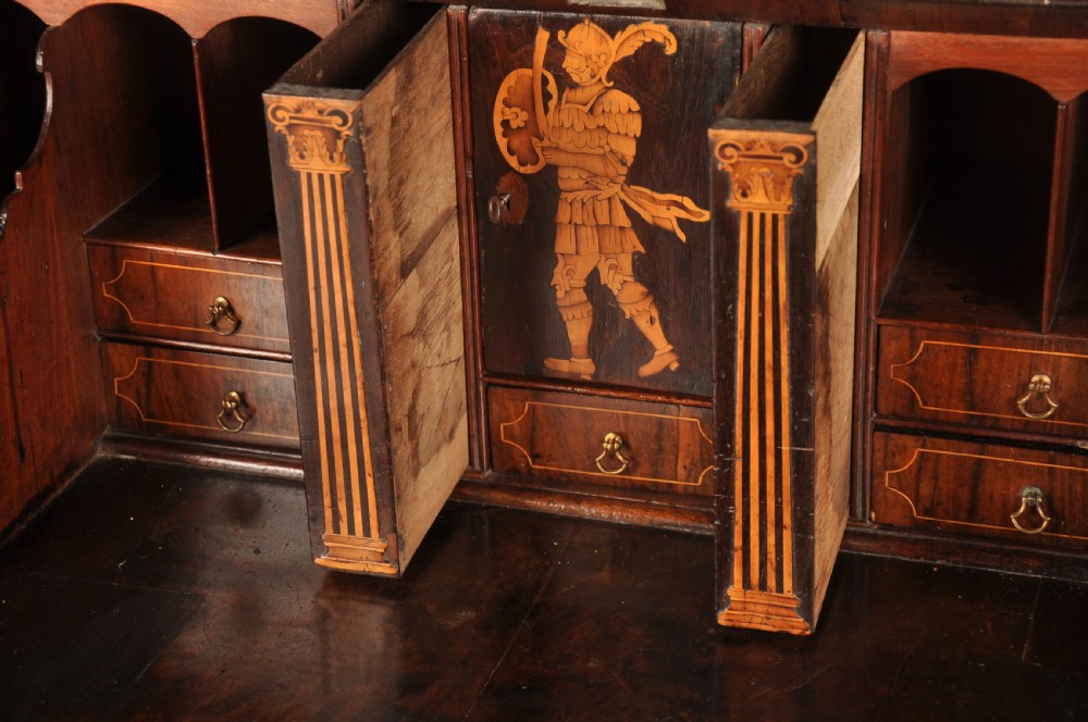 An early 18th-century Irish walnut slant-front bureau featuring engraved brass drop handles, keyhole escutcheons, and bracket feet. View VI