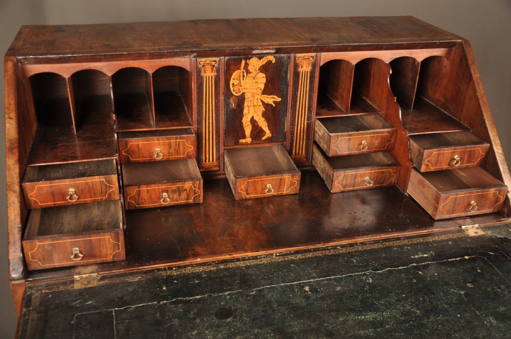 An early 18th-century Irish walnut slant-front bureau featuring engraved brass drop handles, keyhole escutcheons, and bracket feet. View VII