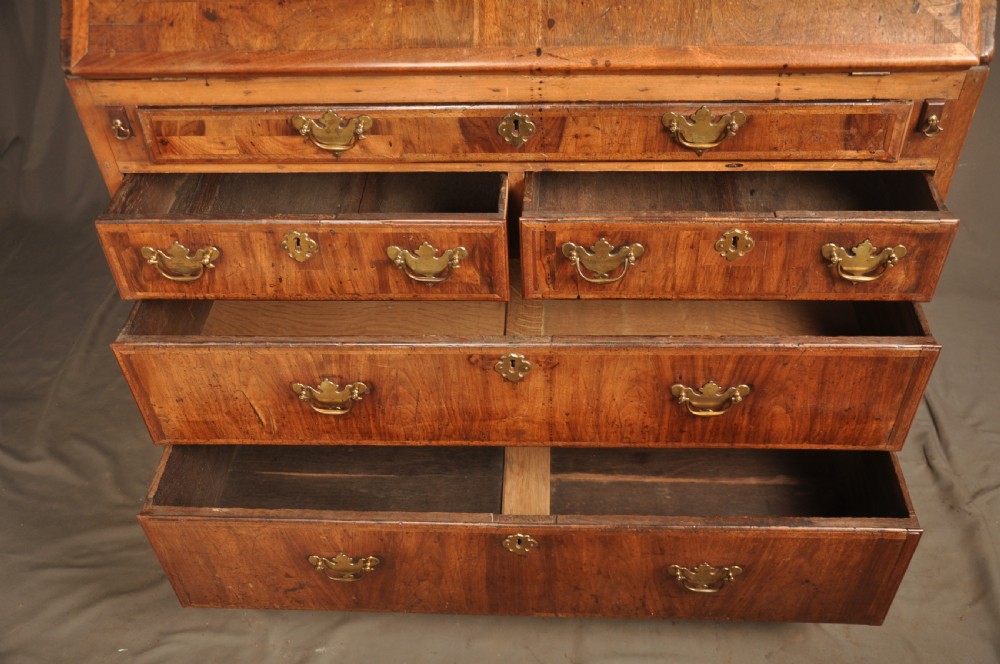 An early 18th-century Irish walnut slant-front bureau featuring engraved brass drop handles, keyhole escutcheons, and bracket feet. View XIII