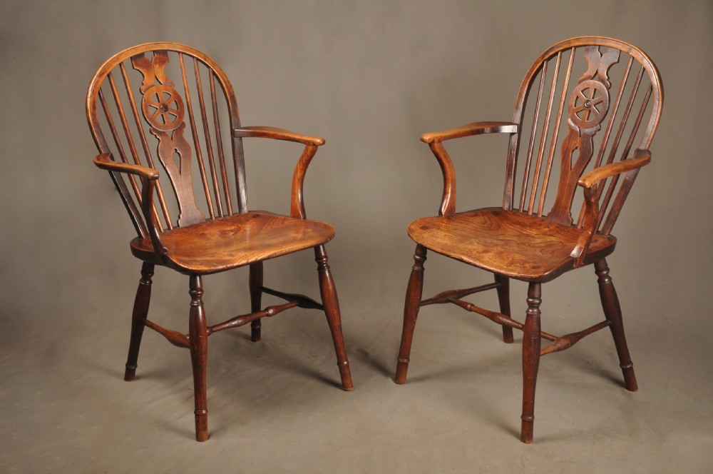 A pair of late 18th-century elm wheelback Windsor armchairs featuring curved backrests with pierced wheel splats, shaped seats, turned legs, and H-stretchers.