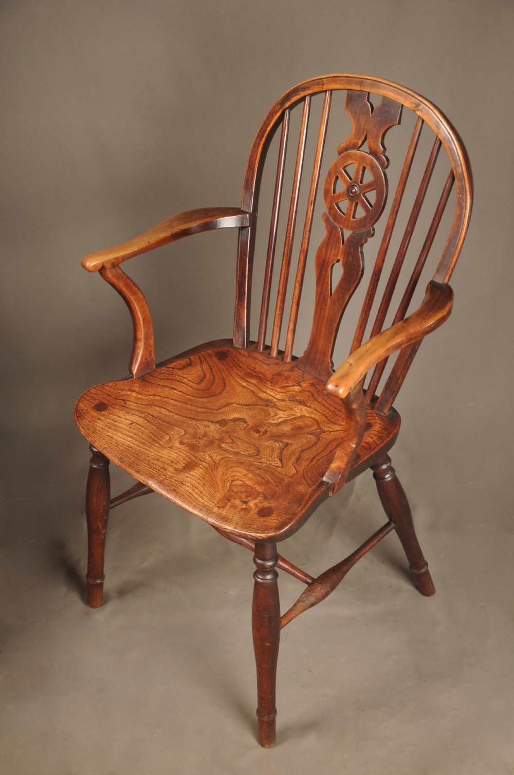 A pair of late 18th-century elm wheelback Windsor armchairs featuring curved backrests with pierced wheel splats, shaped seats, turned legs, and H-stretchers. View VI