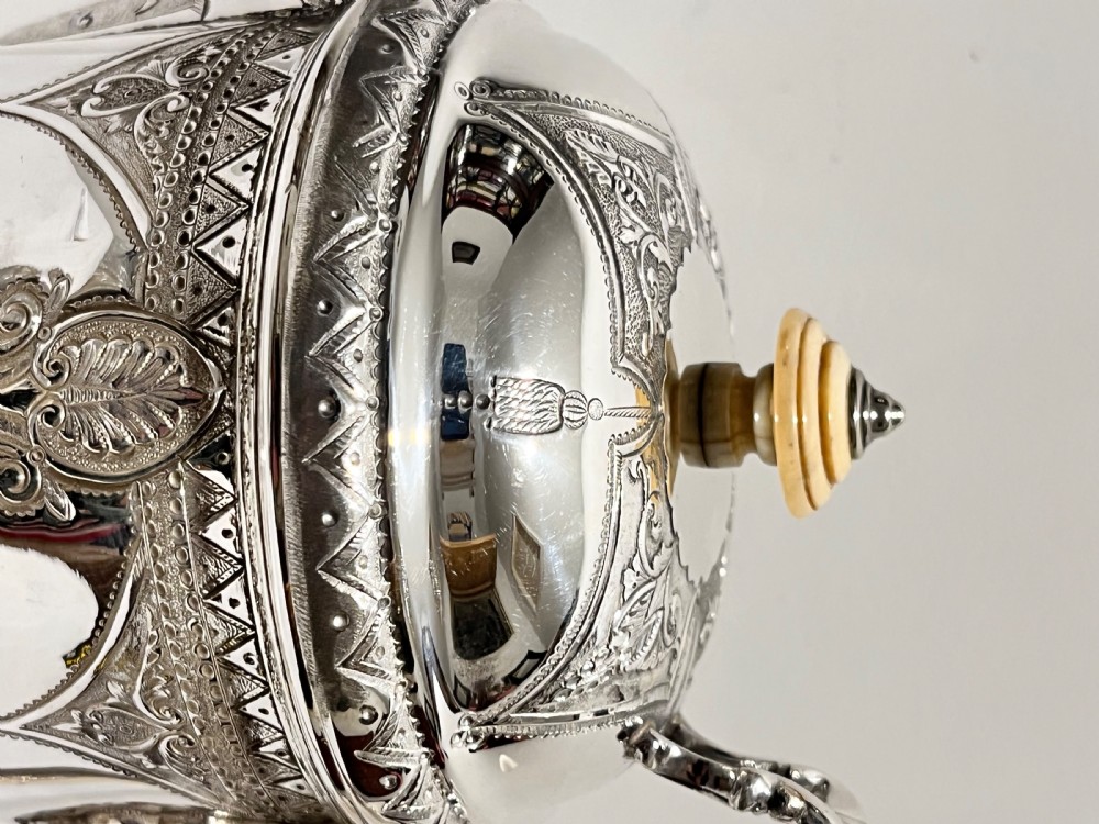 A Victorian lidded silver-plated jug featuring chased floral engraving, a scroll handle with insulating rings, and a hinged lid. View III