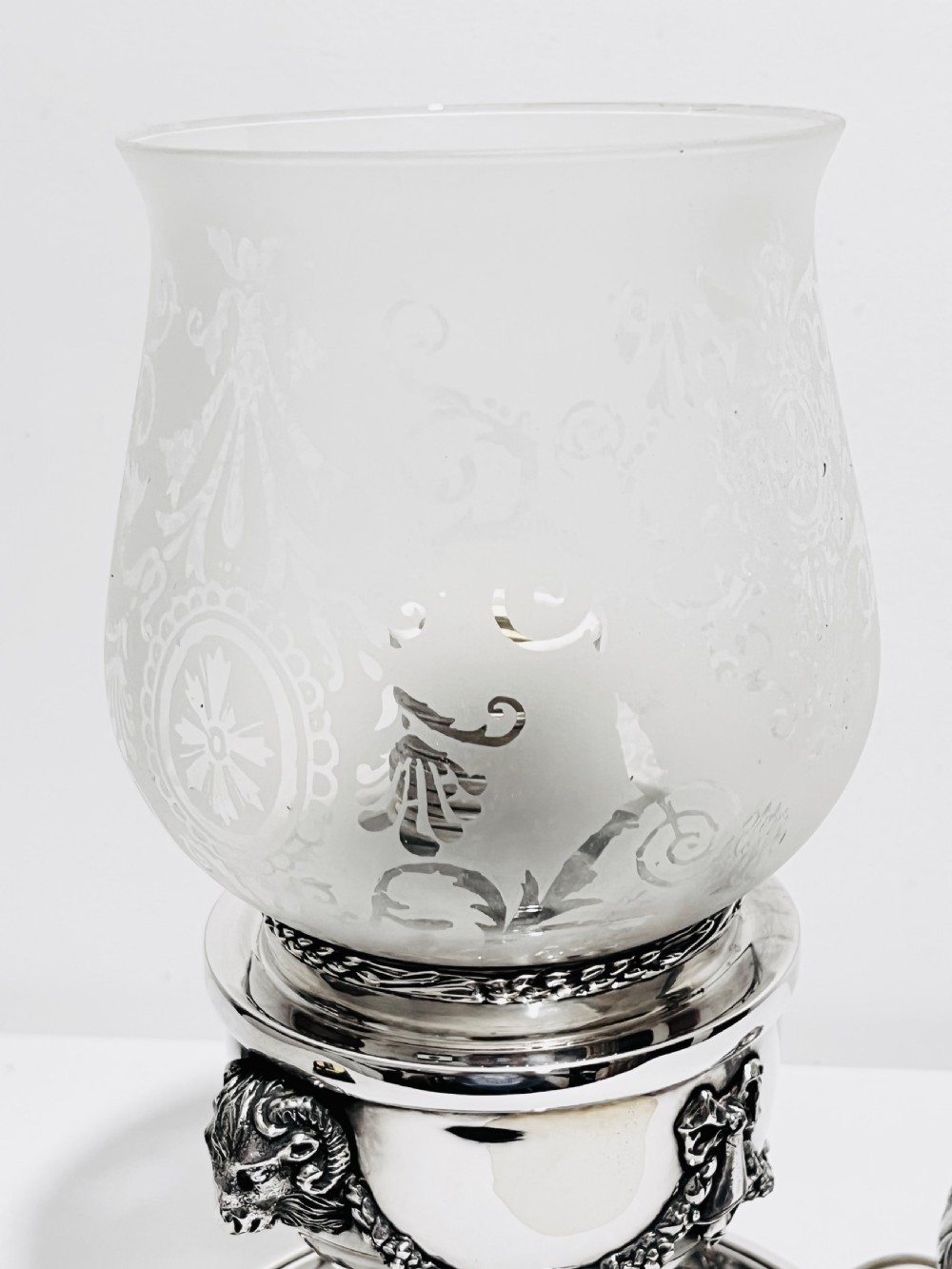 A late nineteenth-century German silver-plated chamberstick style table lamp with an etched frosted glass hurricane shade and a carved lion head motif. View VI