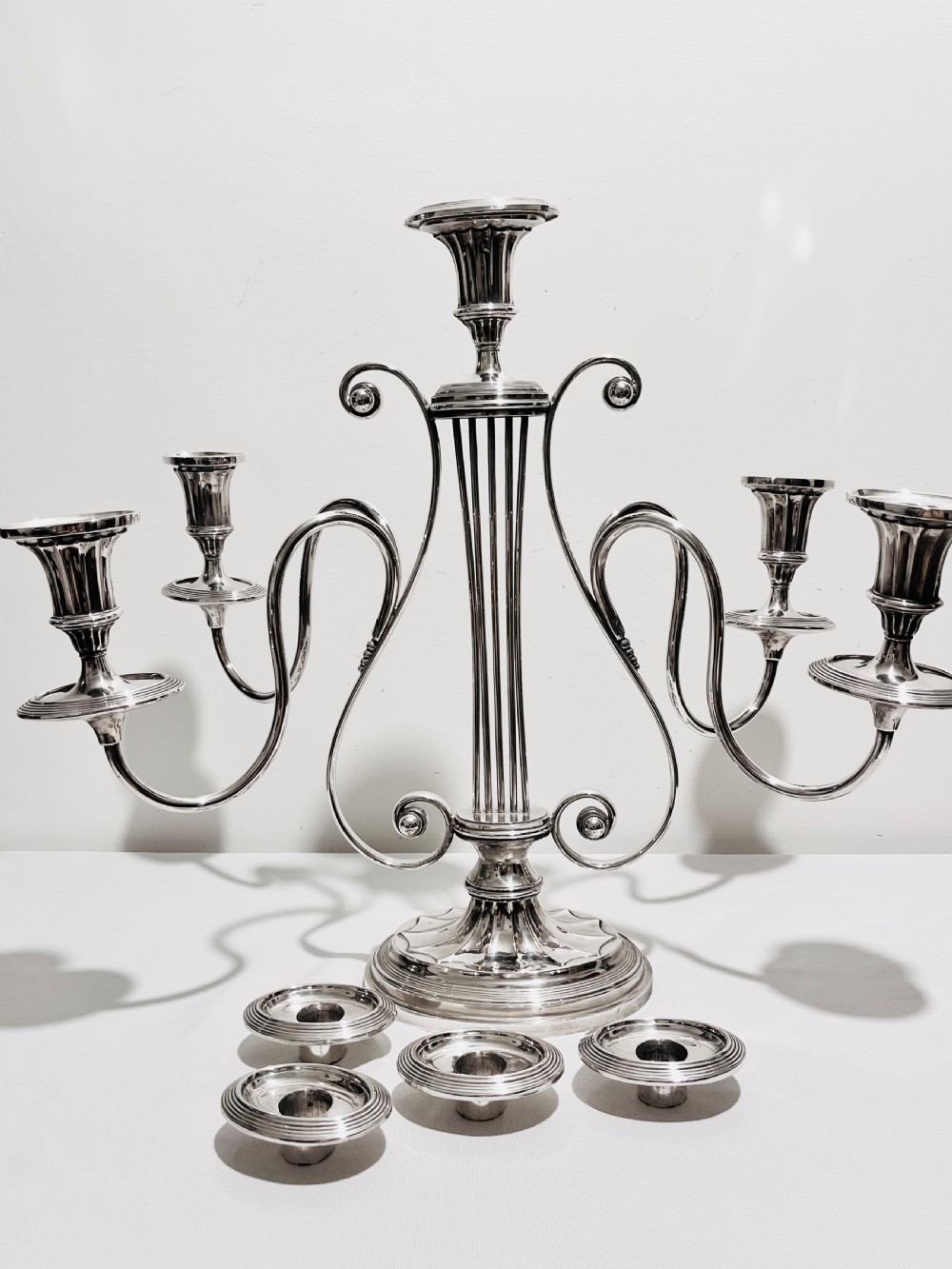 An antique silver-plated five-light candelabra featuring a central lyre-shaped stem with five scrolling branches terminating in circular candle nozzles. View III