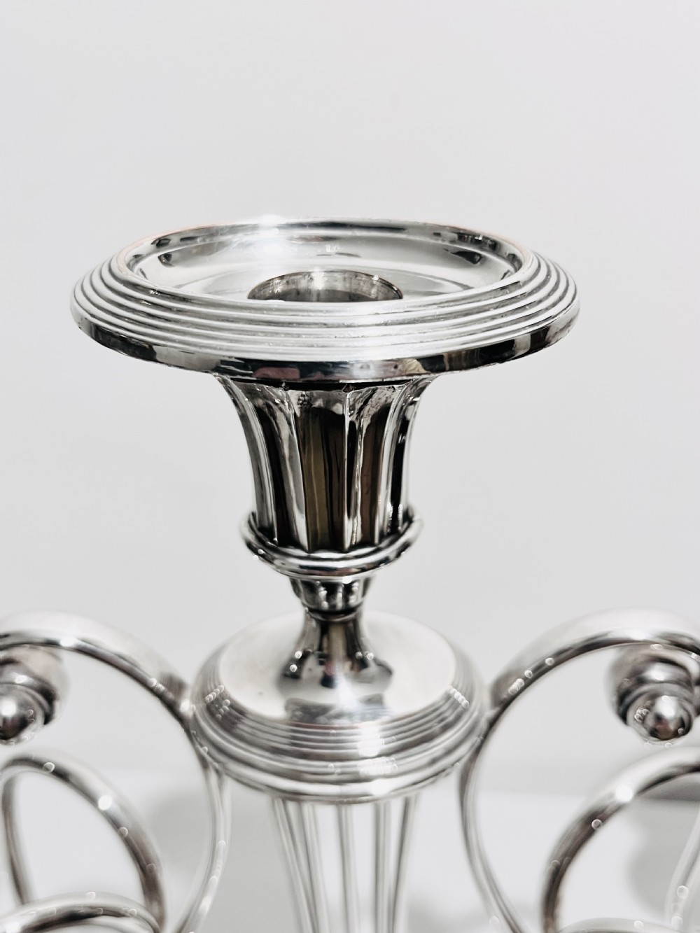 An antique silver-plated five-light candelabra featuring a central lyre-shaped stem with five scrolling branches terminating in circular candle nozzles. View VI