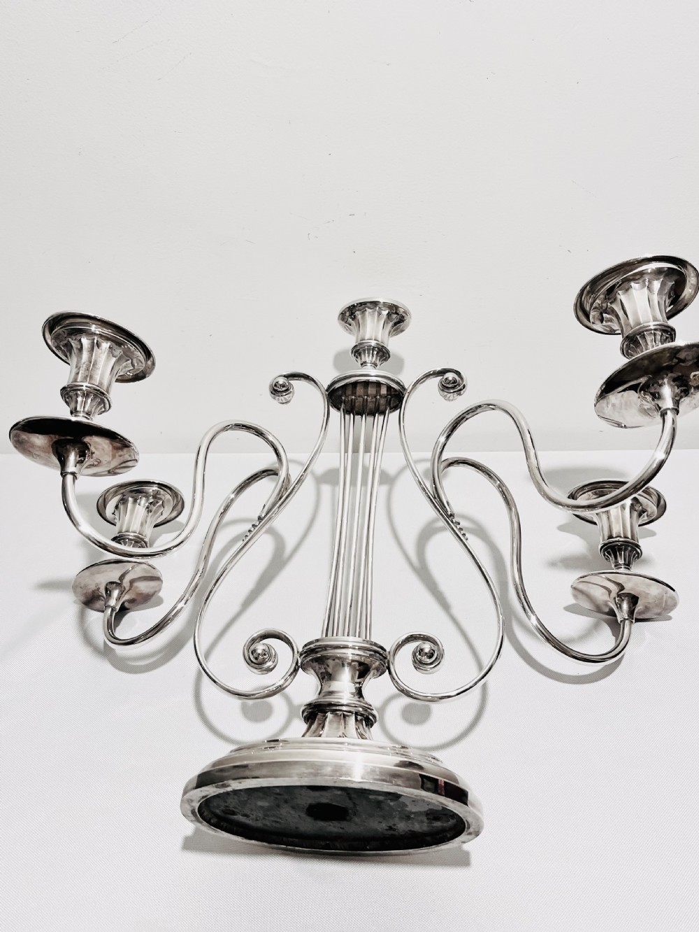 An antique silver-plated five-light candelabra featuring a central lyre-shaped stem with five scrolling branches terminating in circular candle nozzles. View VII